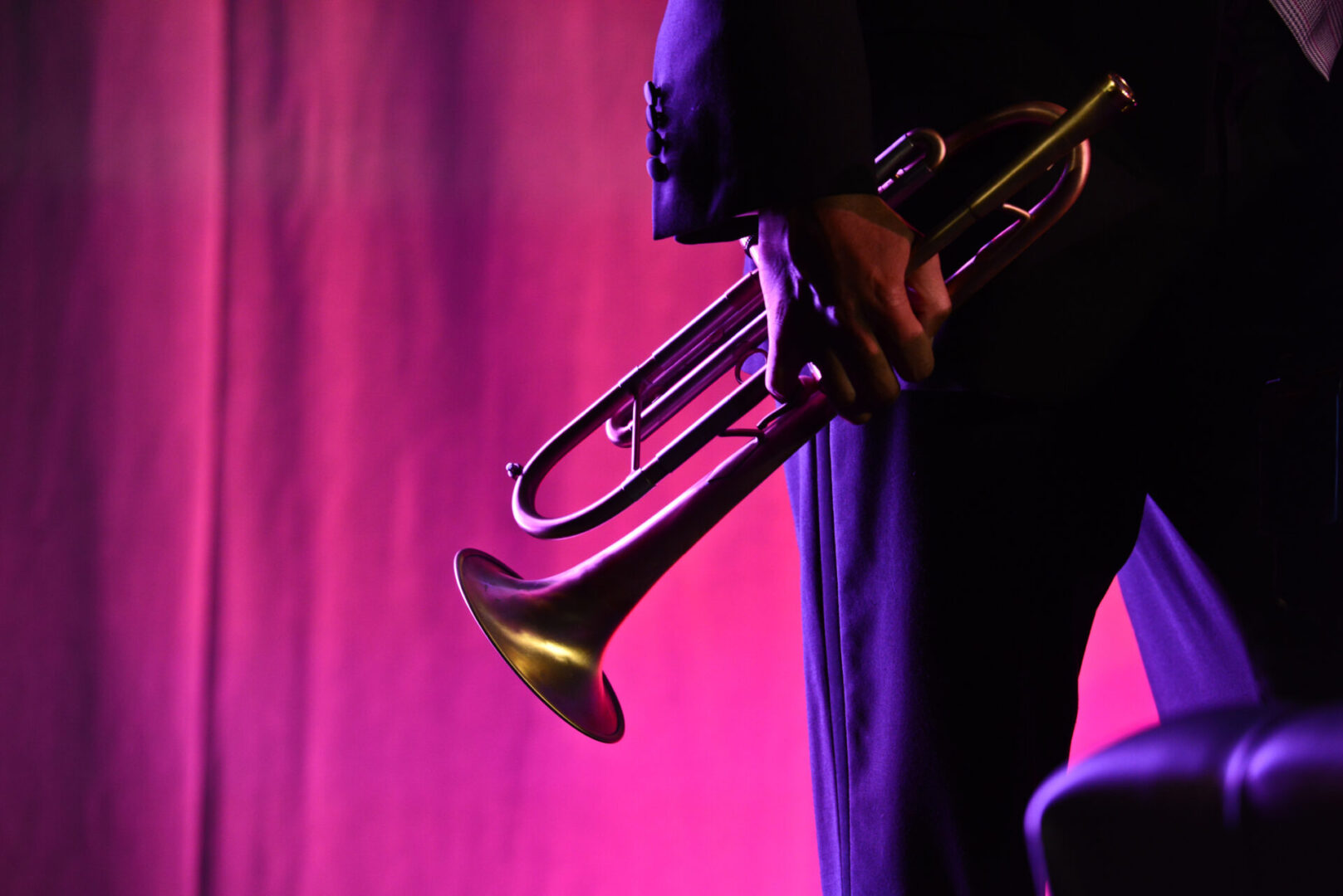 A person playing the trumpet in front of purple lights.