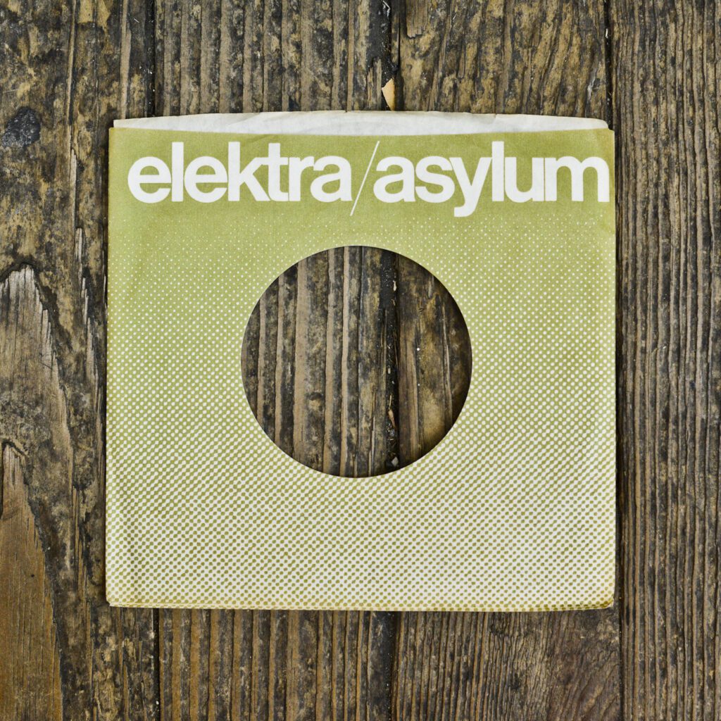 A wooden wall with a square shaped record cover.