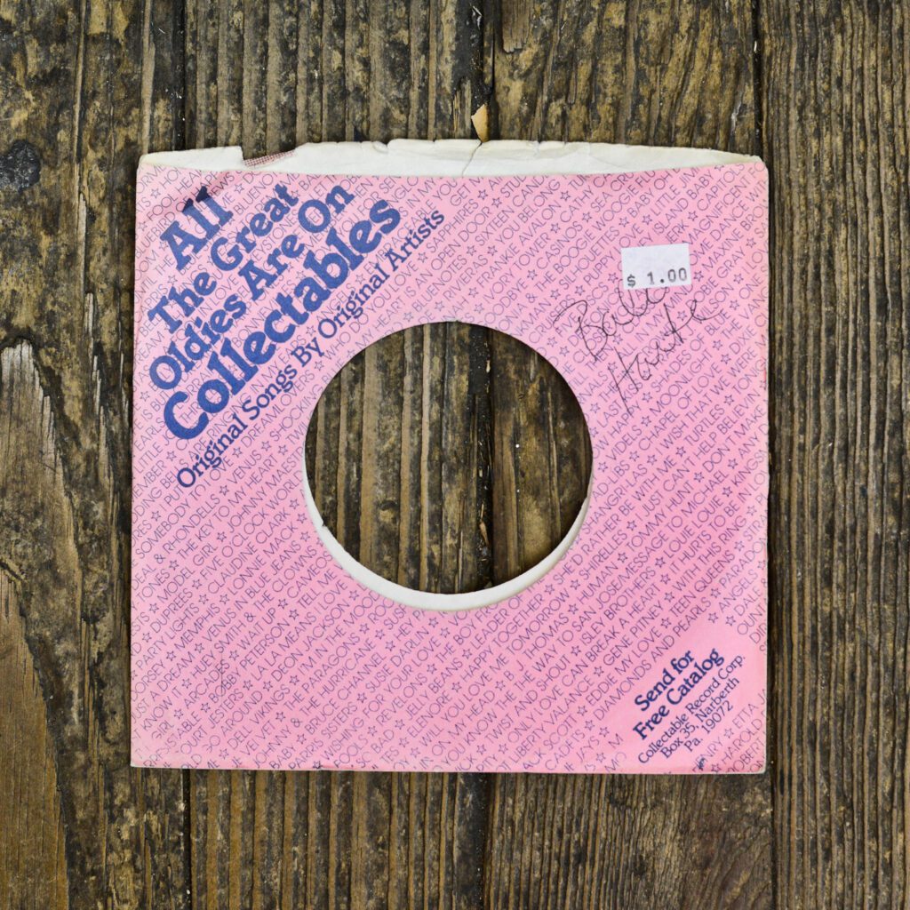 A pink paper record cover sitting on top of a wooden table.